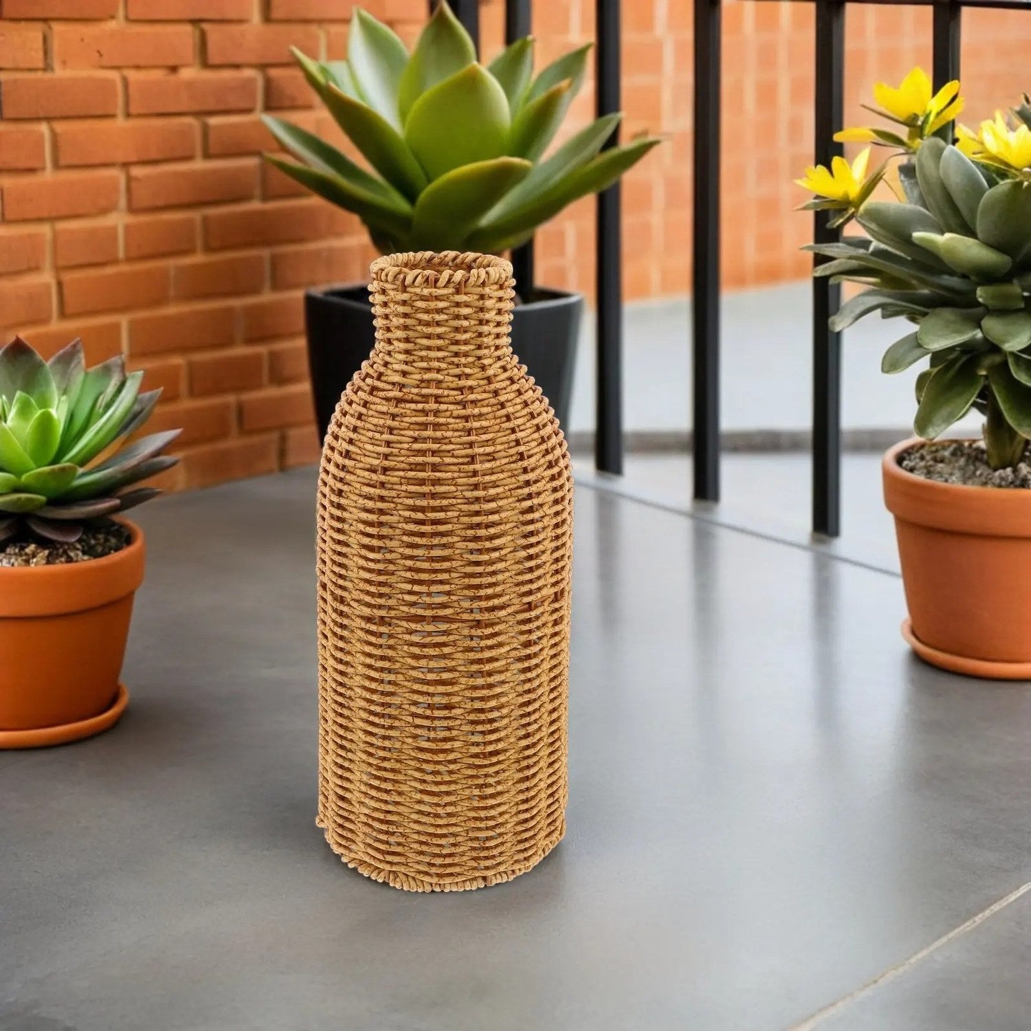 Vase en rotin tressé sur une terrasse en béton devant un mur de briques