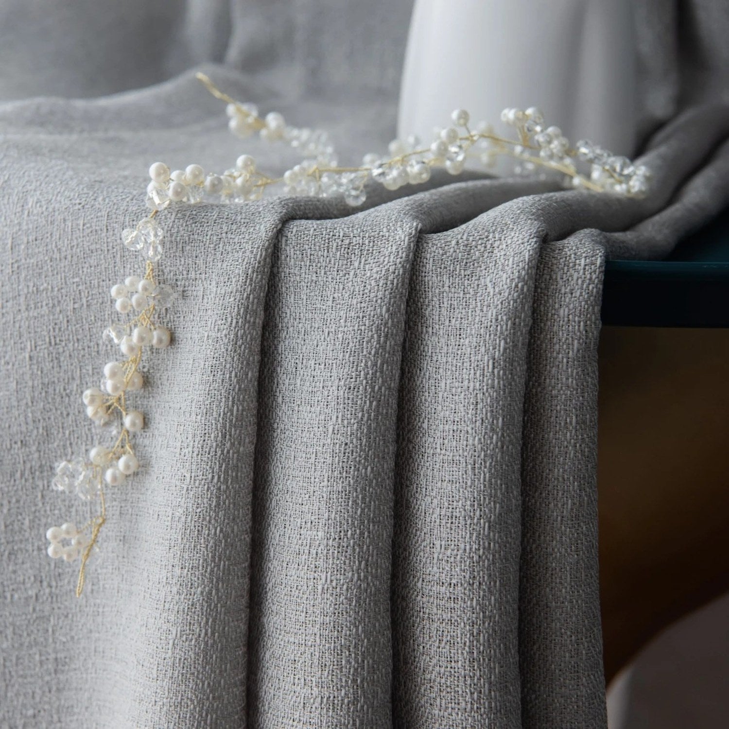 Détail du tissu gris du rideau posé sur une surface avec décoration