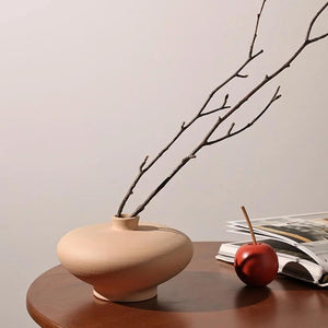 Coupe en céramique terracotta avec branche séchée sur table