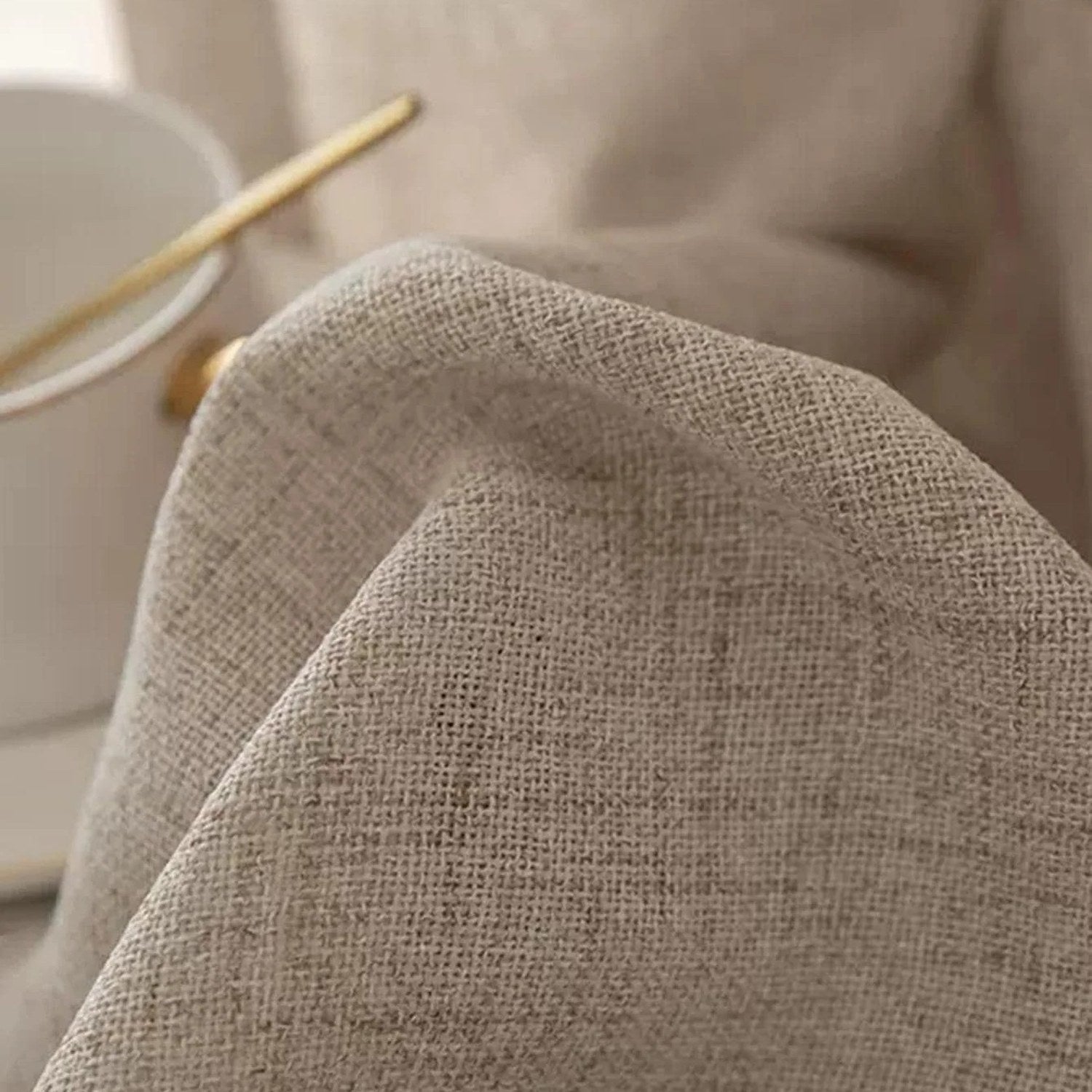 Détail du tissage du rideau beige près d'une tasse et d'un bâton d'encens sur une console