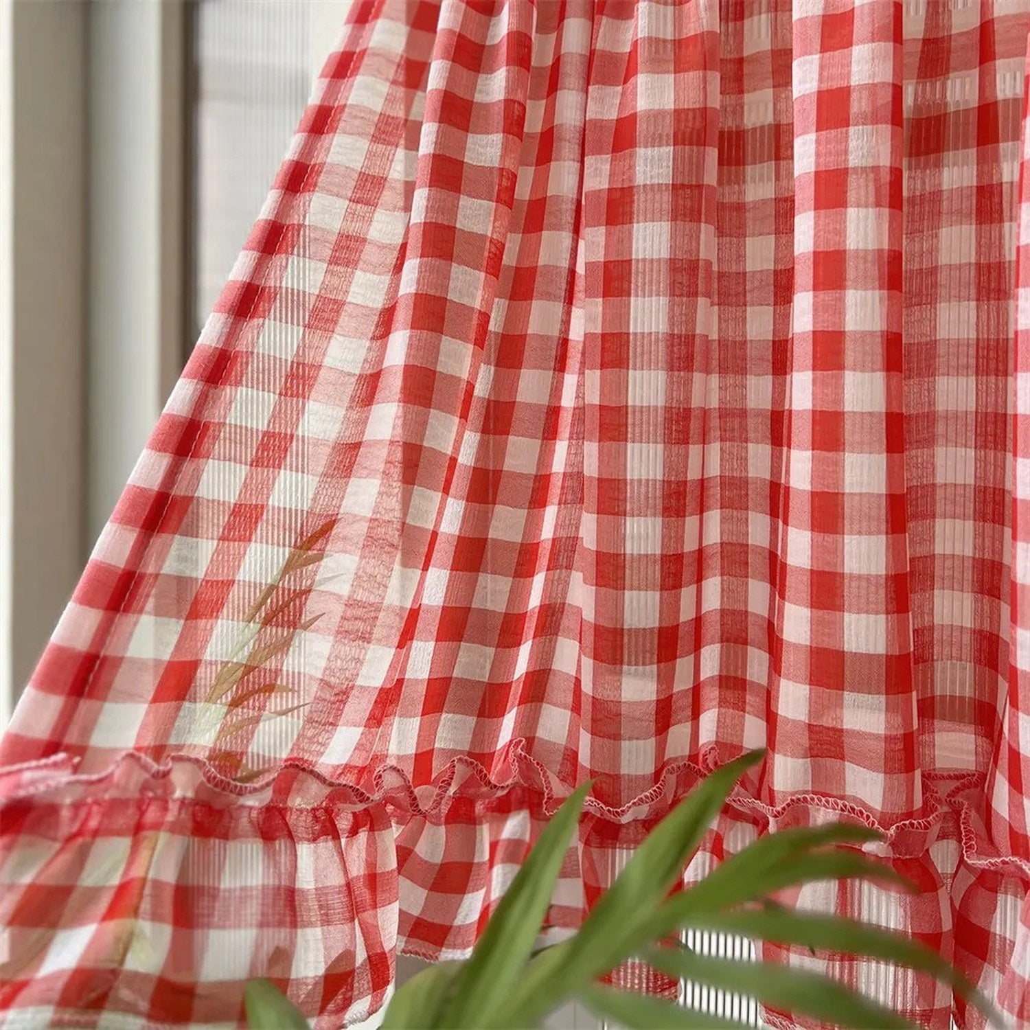 Gros plan sur le tissu voile à carreaux rouges et le volant du rideau
