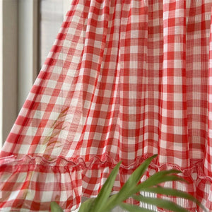 Gros plan sur le tissu voile à carreaux rouges et le volant du rideau