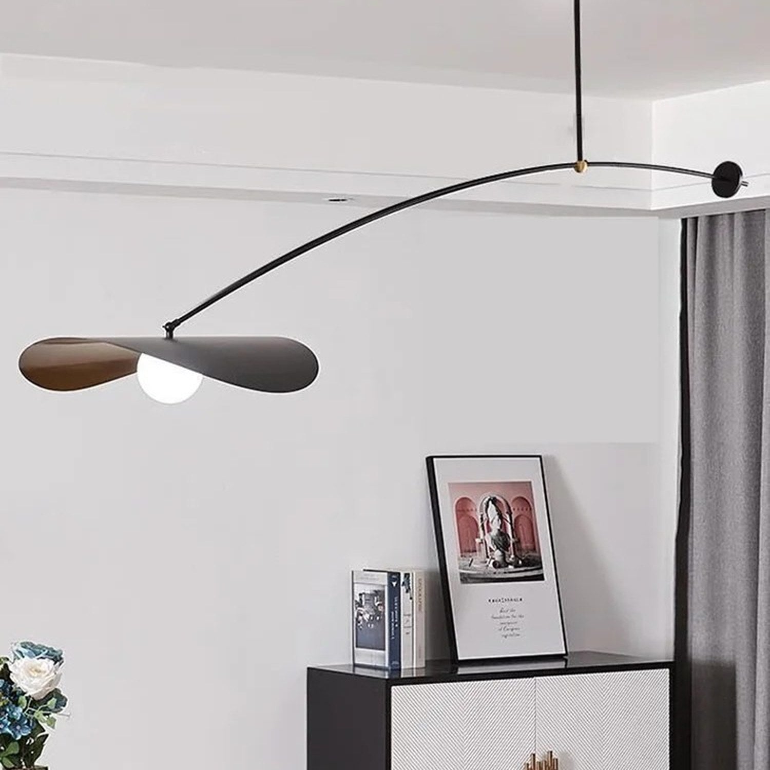 Suspension design éclairant une salle à manger avec vases et livres