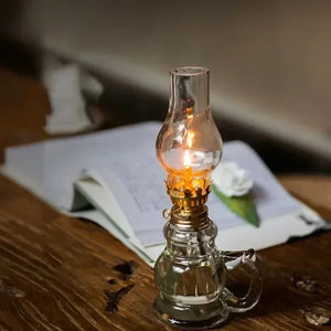 Lampe à pétrole allumée posée sur un bureau en bois avec un livre ouvert