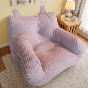 Pouf mini canapé enfant coloris violet posé sur un tapis près d'une table d'appoint