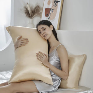 Femme câlinant une taie d'oreiller en soie beige sur un lit