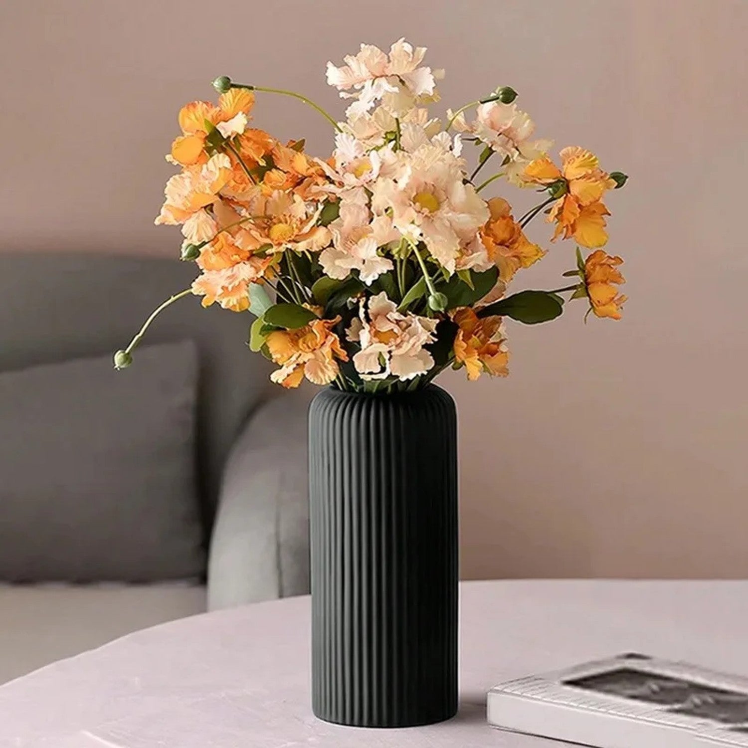 Vase noir à rainures avec fleurs séchées dans un salon