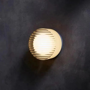 Applique murale LED ronde blanche côtelée gros plan sur mur sombre