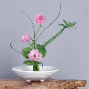 Vase japonais en céramique blanche garni de fleurs sur un socle en bois