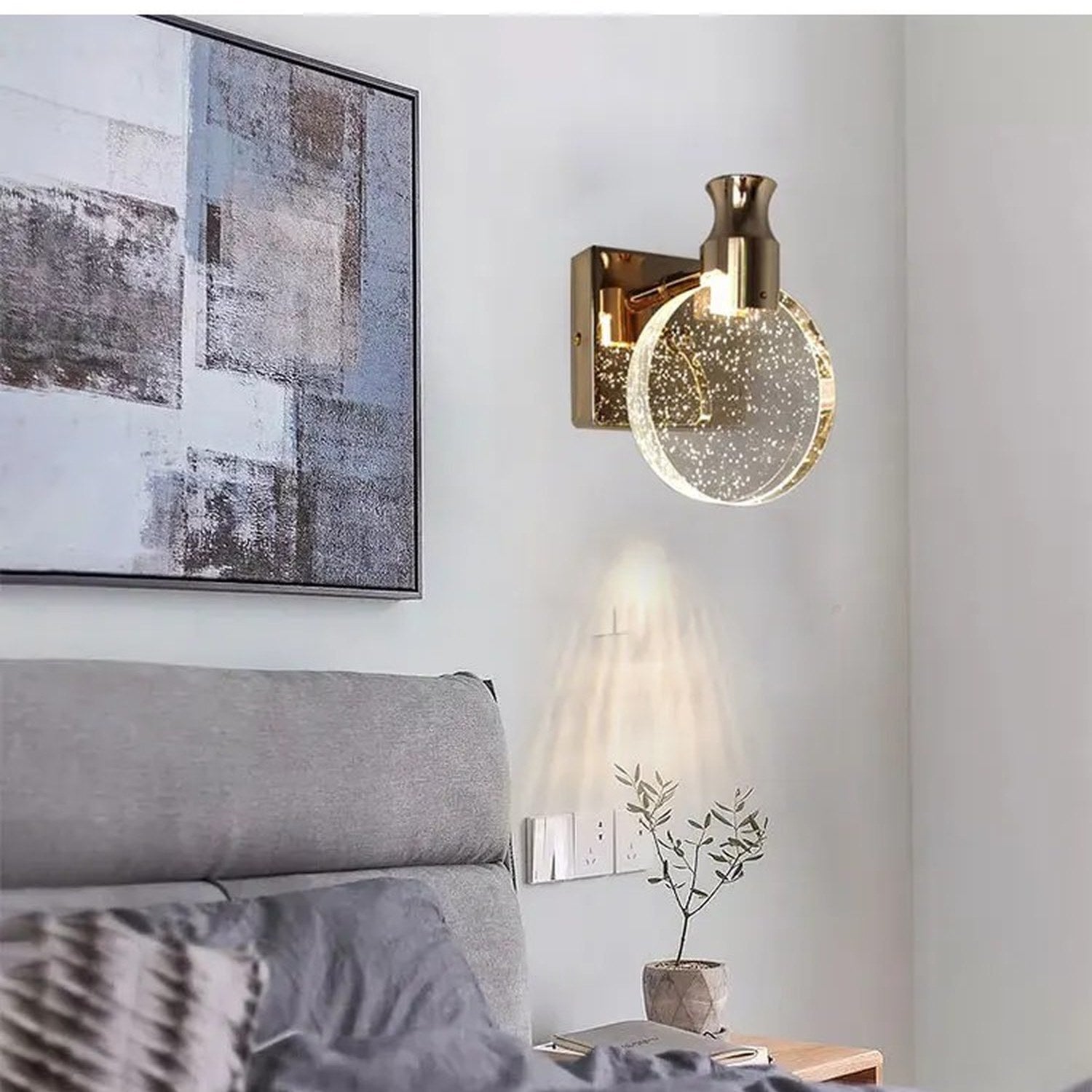 Applique murale dorée installée dans une chambre au-dessus d'une tête de lit