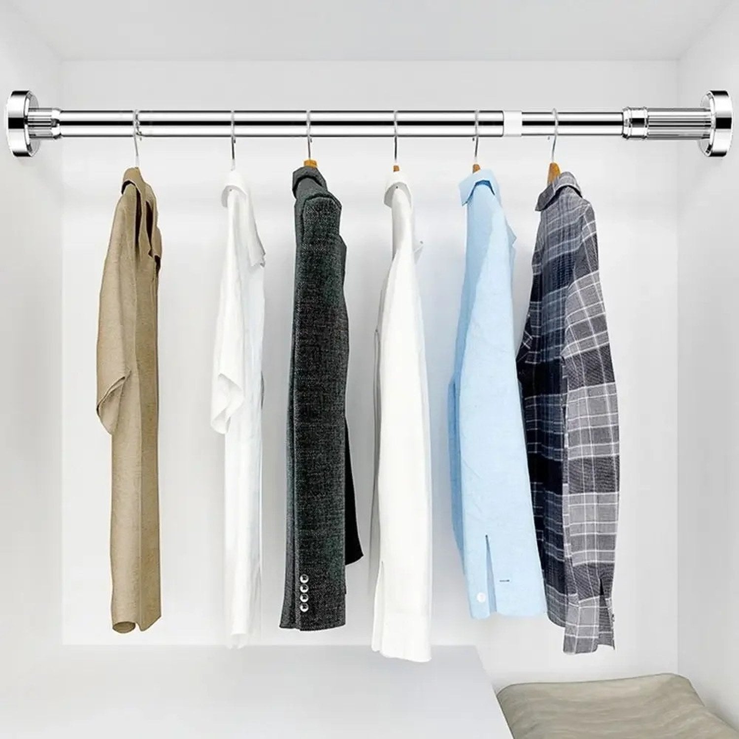 Tringle télescopique chromée utilisée comme penderie dans un dressing avec vêtements sur cintres