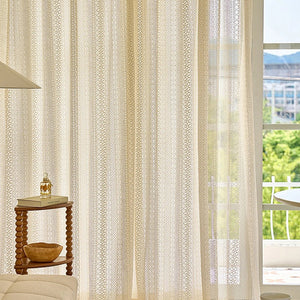 Voilage beige du sol au plafond près d'une porte fenêtre avec vue sur un balcon