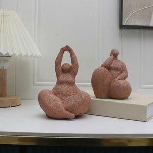 Deux statuettes de femme en résine sableuse terracotta sur table avec lampe et cadre