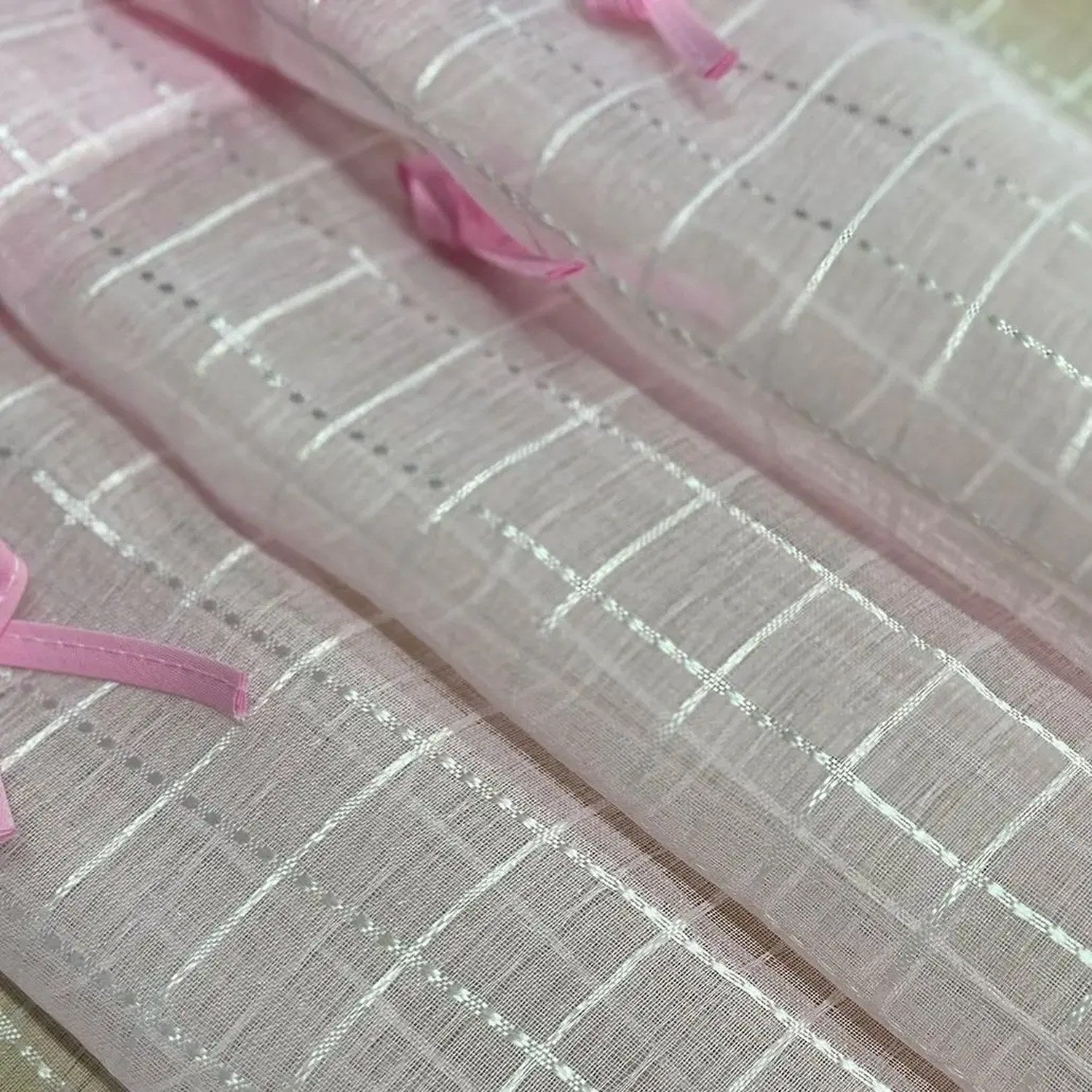 Macro de la maille tulle rose montrant le tissage à carreaux blancs