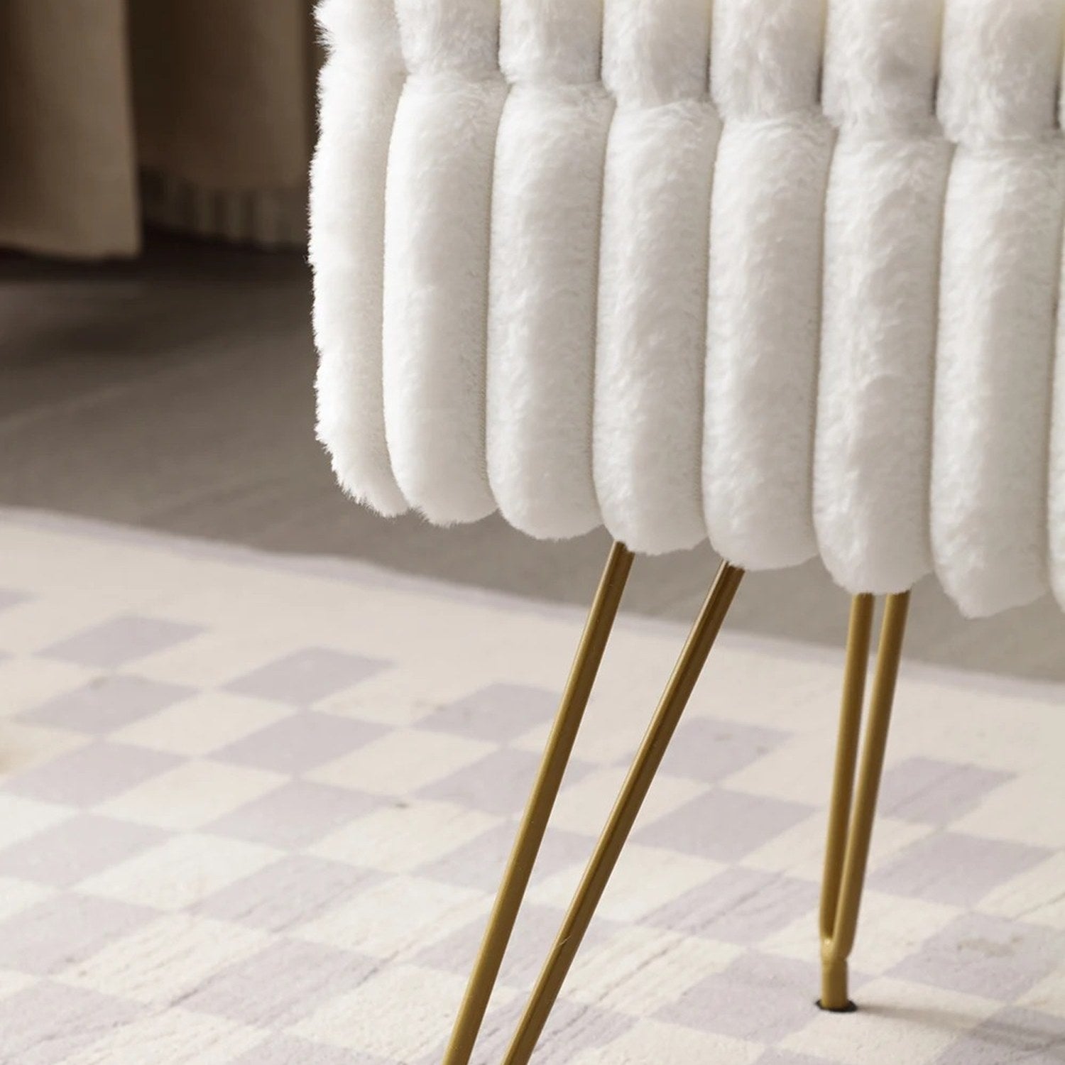 Gros plan sur la fausse fourrure blanche et les pieds en métal doré du tabouret
