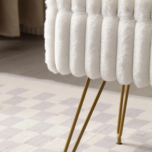 Gros plan sur la fausse fourrure blanche et les pieds en métal doré du tabouret