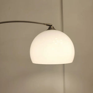 Gros plan du dôme en verre blanc et du bras chromé du lampadaire arc
