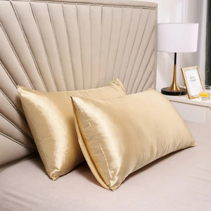 Taies d'oreiller dorées en satin sur un lit chaleureux avec lampe de chevet