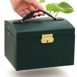 Boîte à bijoux vert foncé fermée tenue par sa poignée avec serrure dorée