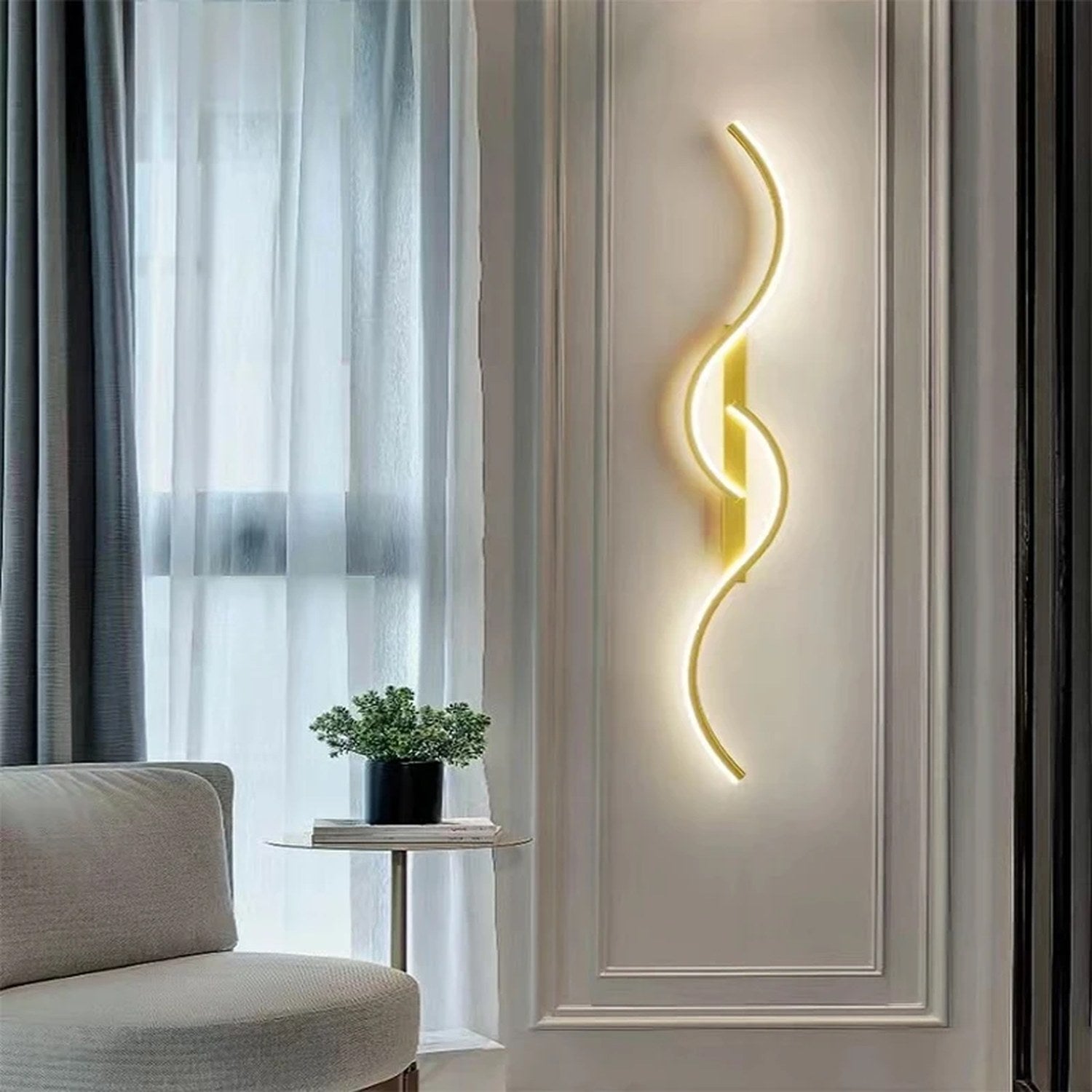 Applique murale LED dorée sur un mur clair à côté d'un fauteuil et d'une plante