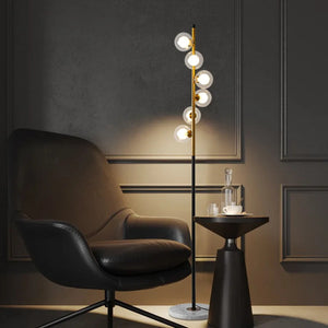Lampadaire à boules de verre ambré allumé projetant une lumière chaude dans un salon sombre