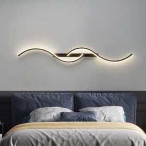 Applique murale LED noire posée à l'horizontale au-dessus d'un lit