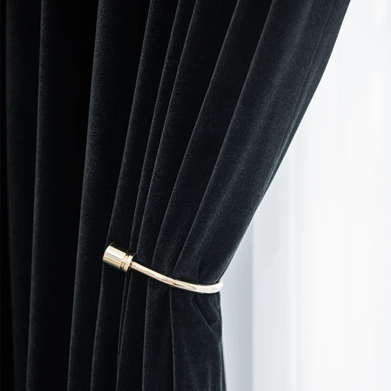 Détail de la texture veloutée du rideau noir avec embrasse dorée