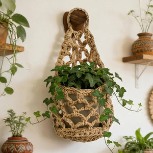 Panier suspendu macramé marron avec plante grimpante lierre sur mur blanc style bohème