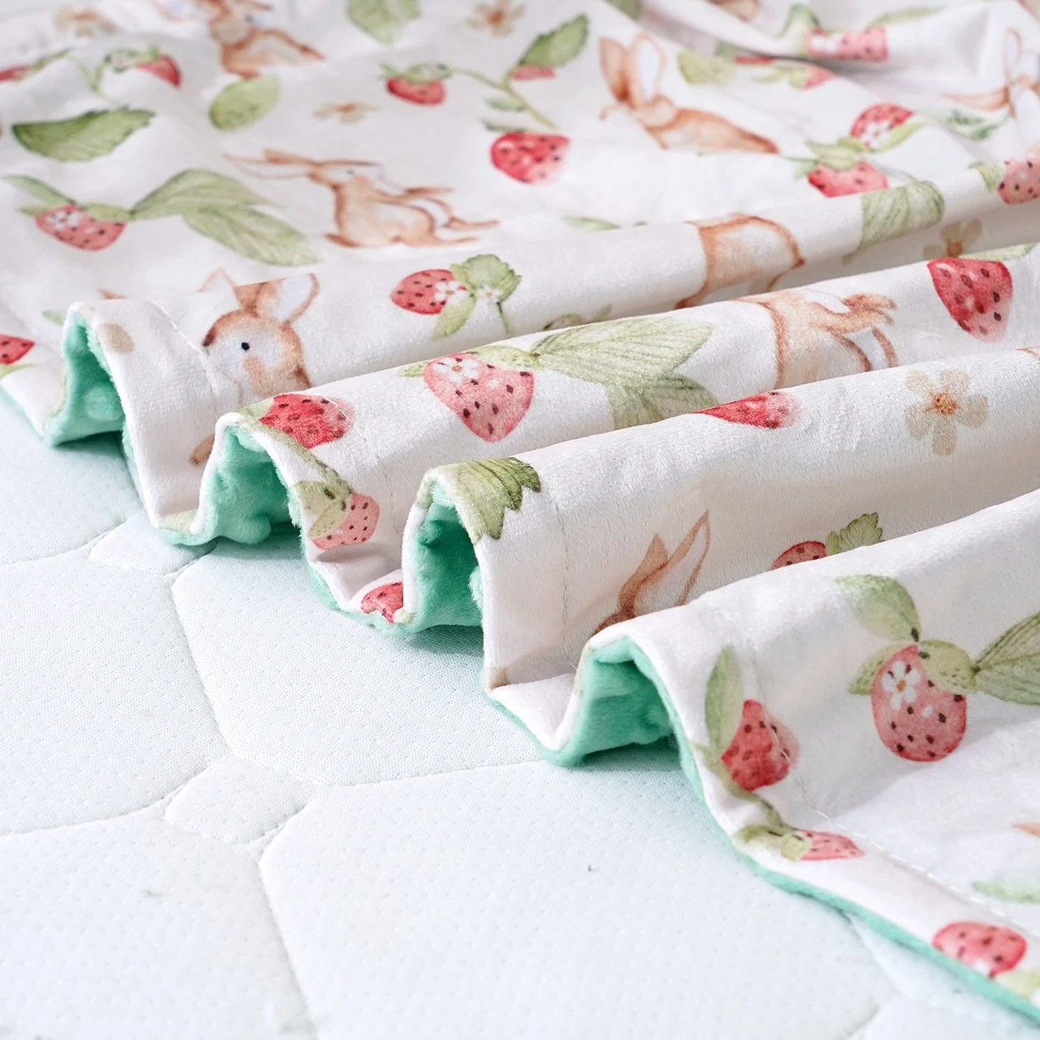 Gros plan sur la face à pois en relief et le motif lapins de la couverture bébé