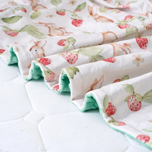Gros plan sur la face à pois en relief et le motif lapins de la couverture bébé