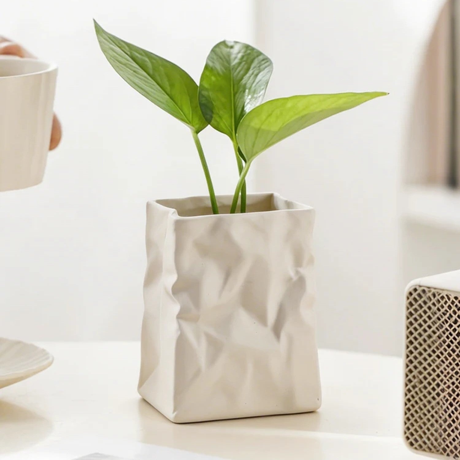 Vase résine froissée blanc avec plante verte sur bureau bois