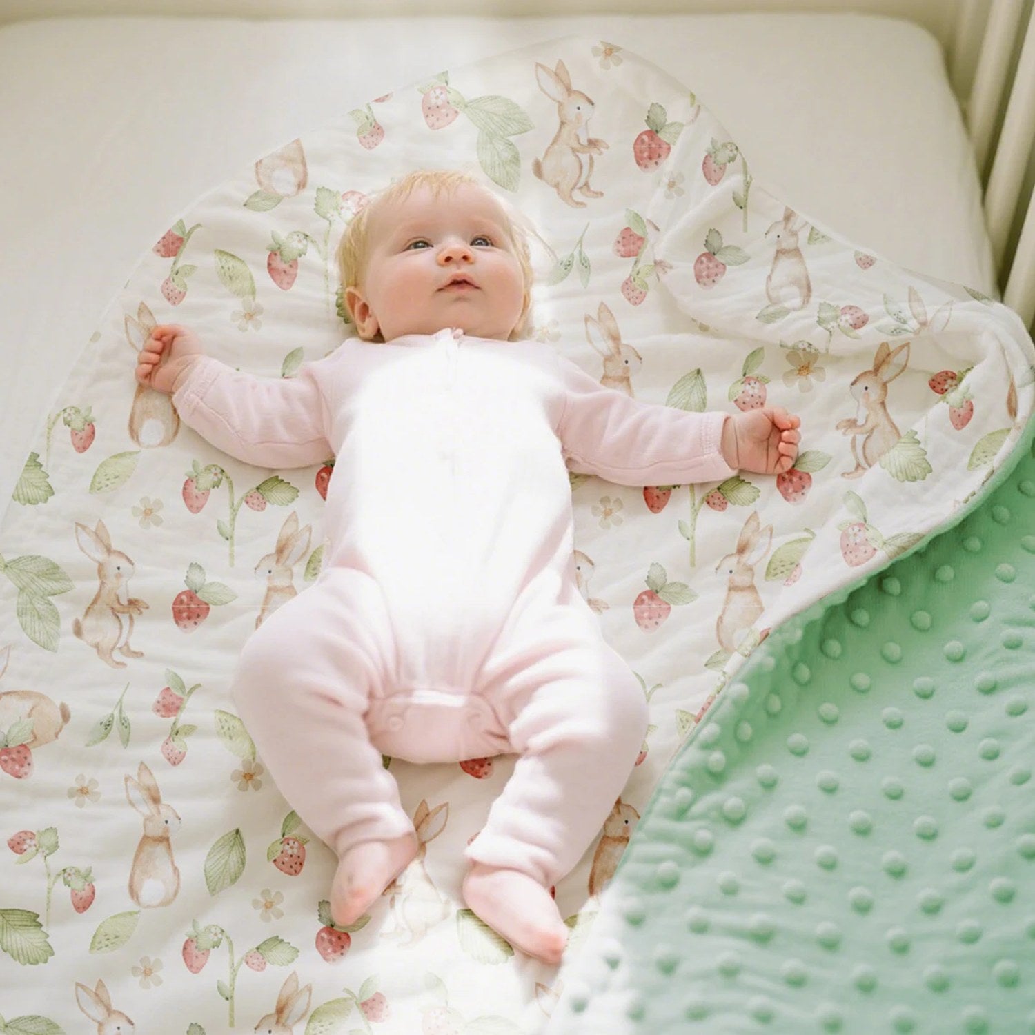 Bébé allongé sur la couverture bébé à motif lapins dans son lit