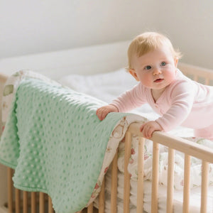 Bébé dans son lit avec la couverture bébé au dos à pois vert menthe