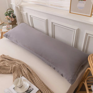 Taie de traversin gris sur un lit avec une personne allongée à côté