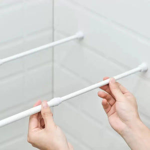 Installation d'une tringle extensible blanche entre deux murs carrelés