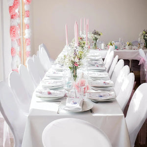 Longue table de mariage avec chaises blanches et bouquets de fleurs champêtres vue de face