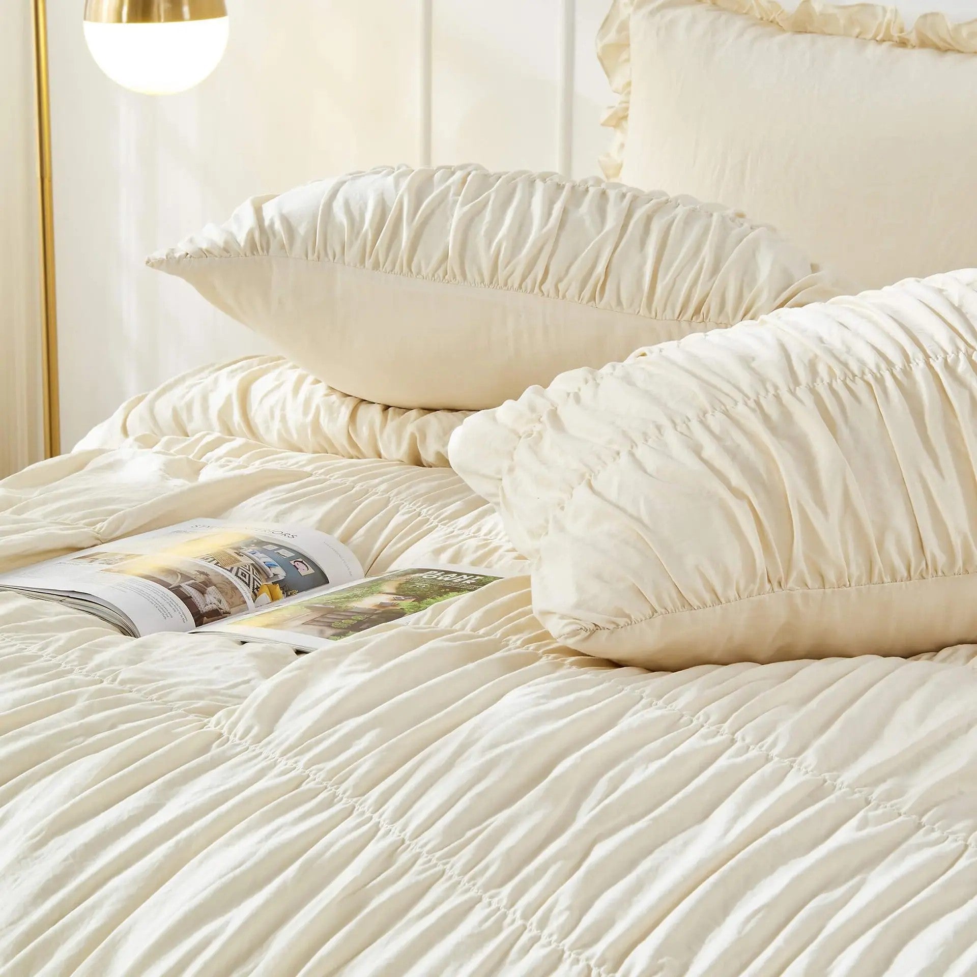 Parure de lit bohème chic sur un lit avec magazine déco et lampe dorée en chambre lumineuse