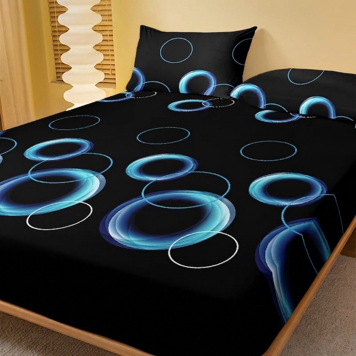 Drap-housse noir à motif de cercles bleus posé sur un lit avec taie assortie non incluse