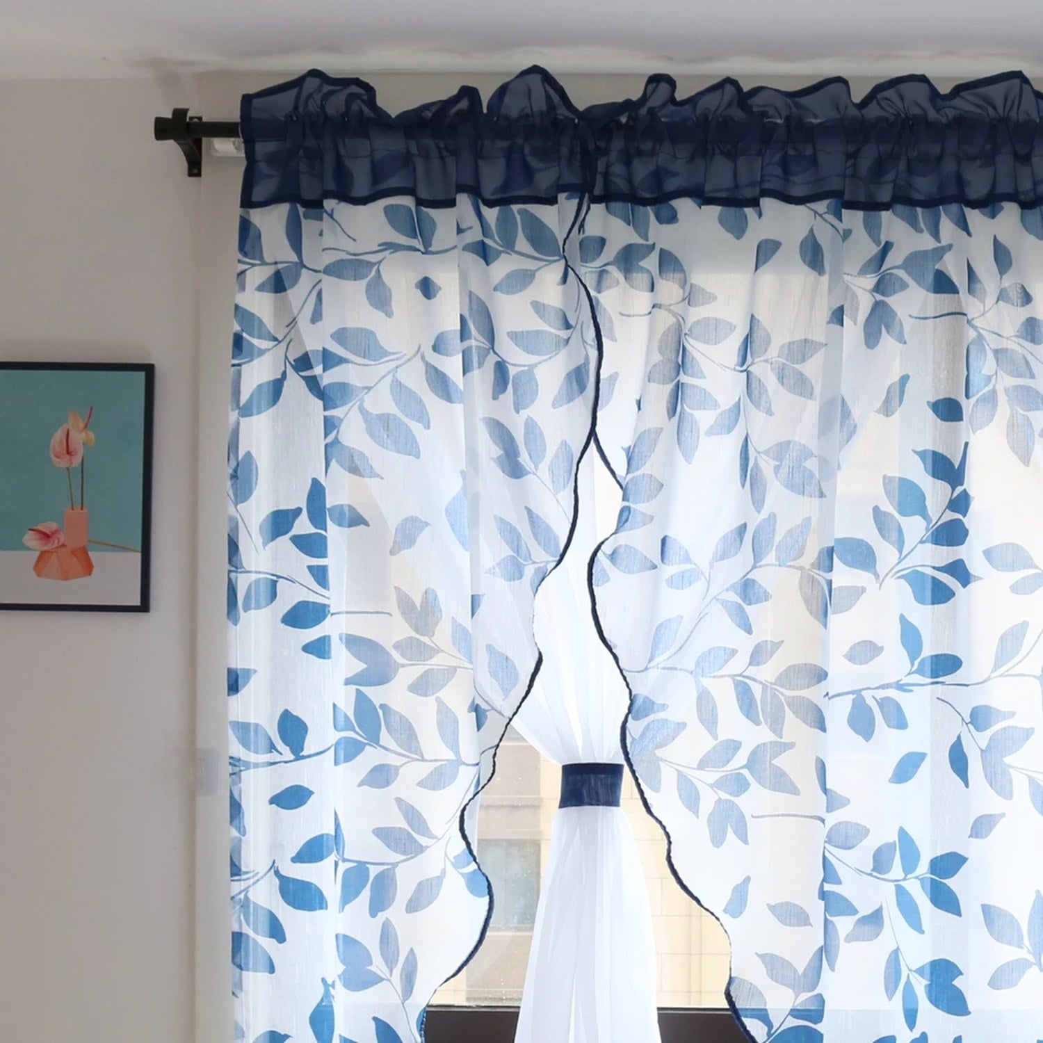 Voilage blanc à motif de feuilles bleues devant une fenêtre