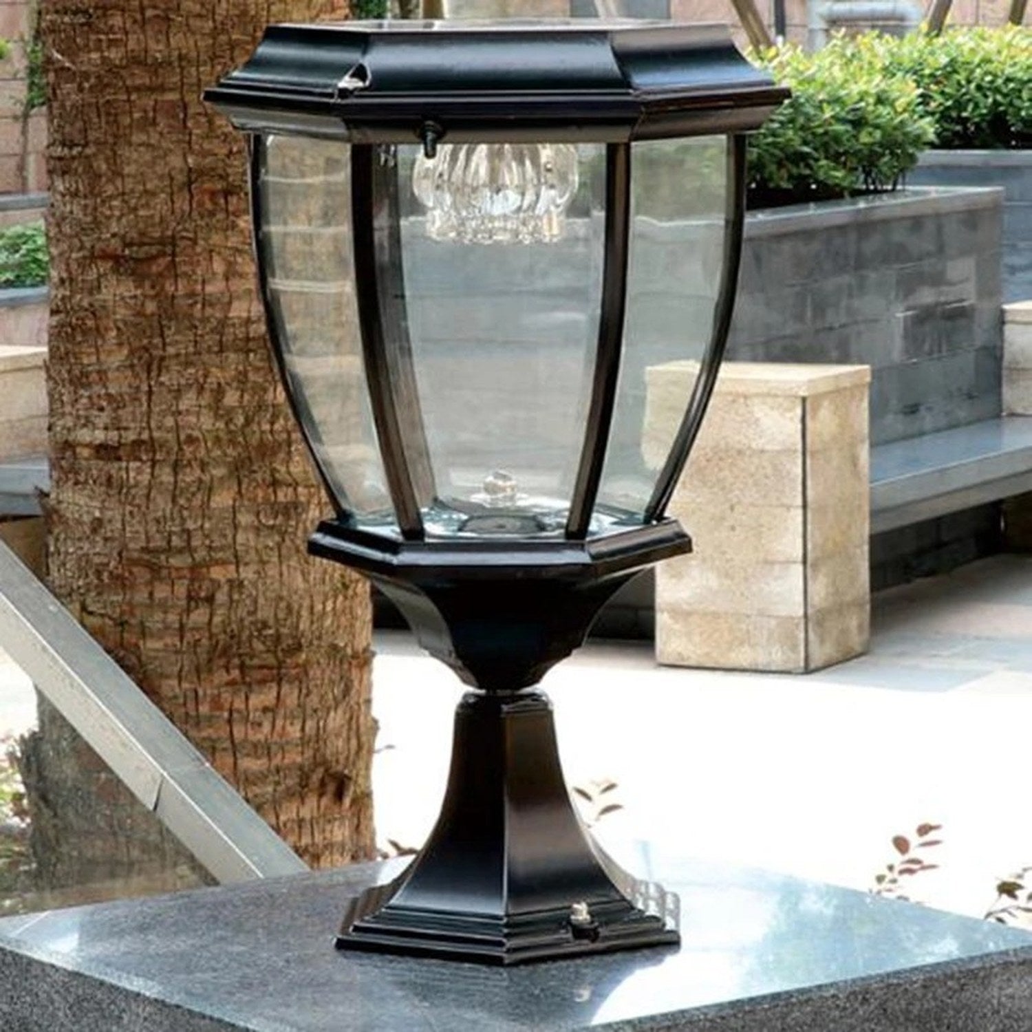 Lanterne solaire noire installée sur un pilier en pierre dans un jardin