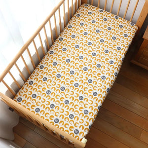 Drap housse bébé motif ourson polaire sur fond moutarde installé sur un matelas de berceau