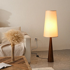 Lampadaire allumé posé au sol près d'un canapé avec pampas