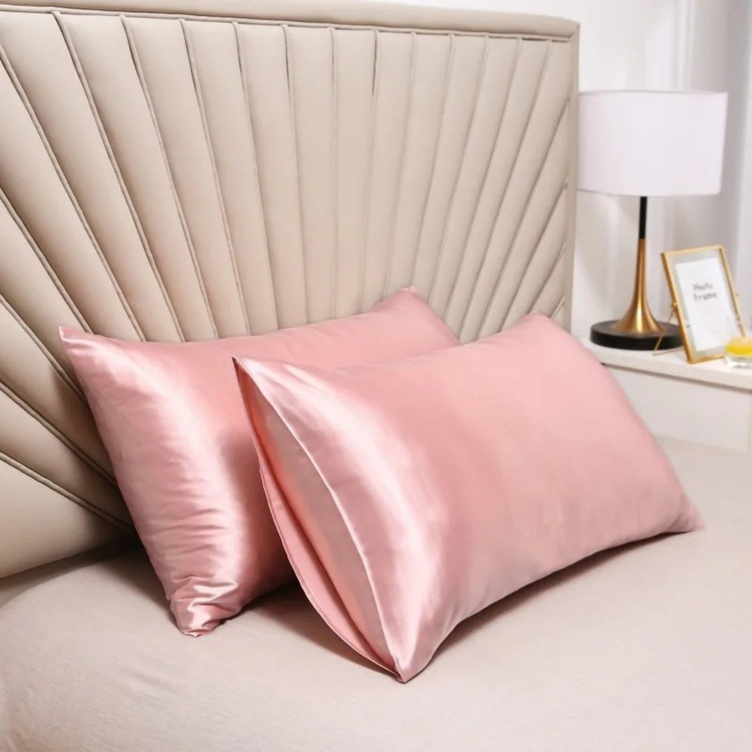 Taies d'oreiller roses en satin disposées sur un lit