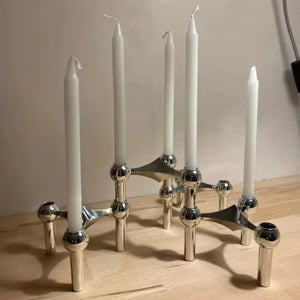 Chandelier modulaire en métal argenté brillant posé sur une table en bois