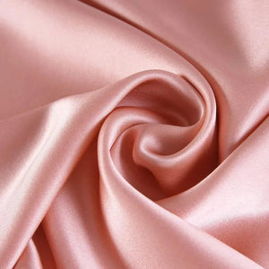 Gros plan sur le tissu de soie rose poudré froissé de la taie d'oreiller
