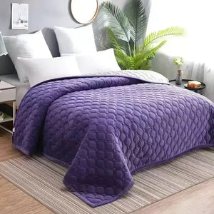 Couvre-lit matelassé violet drapé sur un lit avec une plante verte