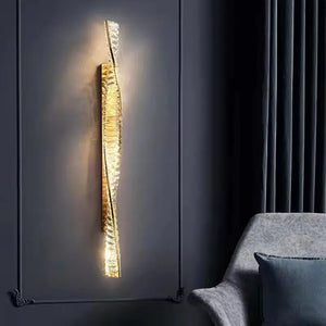 Applique murale dorée en cristal allumée dans une chambre au mur foncé