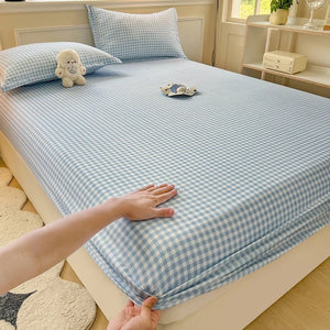 Drap-housse à carreaux bleu posé sur un lit avec taies assorties