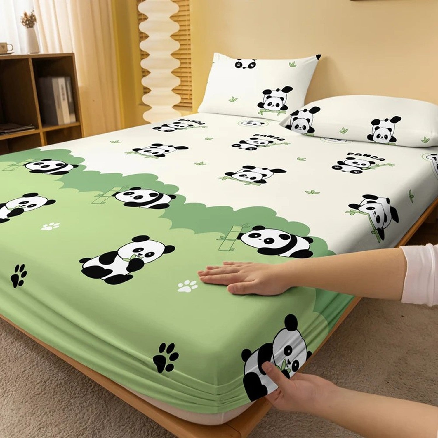 Détail du tissu doux du drap-housse panda avec une main posée sur le matelas