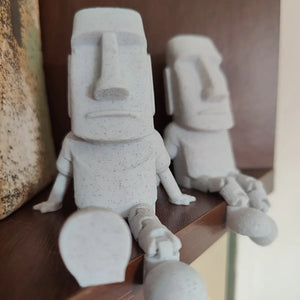 Deux statuettes Moai articulées assises côte à côte sur une étagère en bois